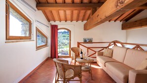 Une pièce chaleureuse avec un plafond en bois, des meubles en osier et une vue sur l’extérieur, visible à travers une porte.