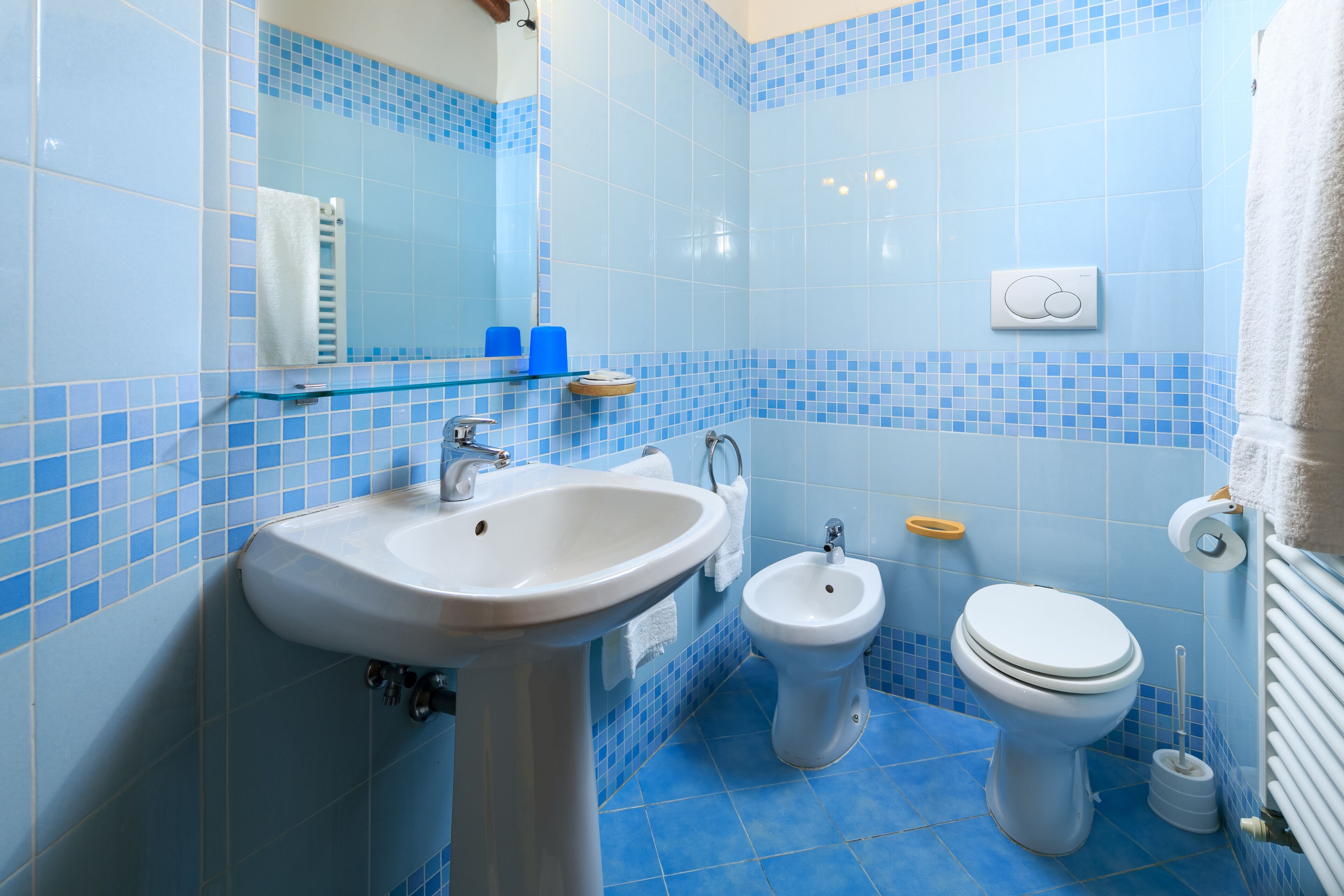 Ein Badezimmer mit Waschbecken, Bidet und Toilette, alles mit blau gefliesten Wänden und Boden.