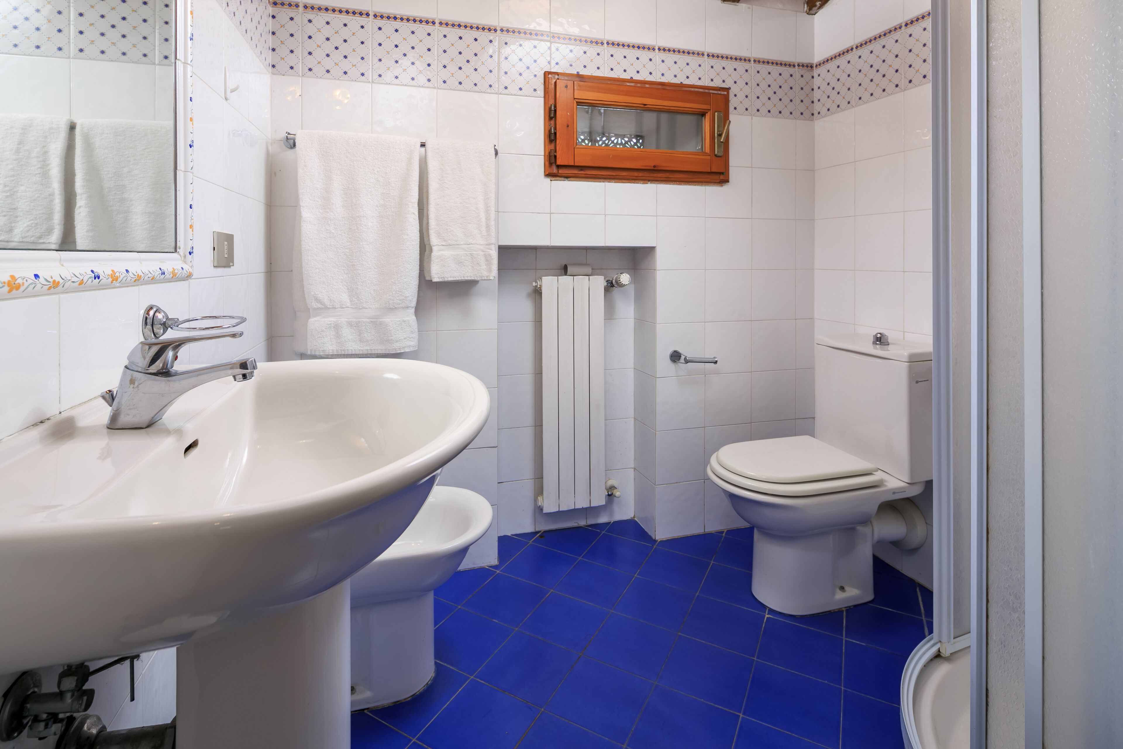 Ein Badezimmer mit Waschbecken, zwei Toiletten, einem Spiegel und einem Fenster.
