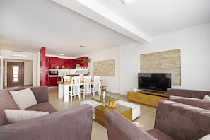 Un salon moderne avec un canapé, une table basse et un téléviseur. Il y a également un coin repas avec une table et des chaises.