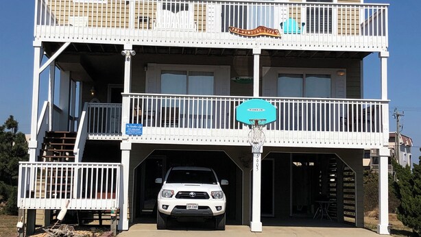 A two-story building with a balcony, a garage, and a sign that reads "The Sandoval Life." - 5 BR Nags Head second row beach house  (Nags Head)