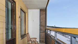 A balcony with wooden chairs, a glass door, and a view of a snowy landscape. - Ylläs chalets 2301 by Interhome (Ylläsjärvi)