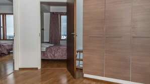 A bedroom with a wooden wardrobe, a bed with a patterned bedspread, and a view of the outside through a window. - Ylläs chalets 2301 by Interhome (Ylläsjärvi)