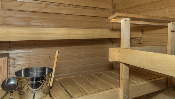 A wooden sauna with benches and a metal basin. - Ylläs chalets 2301 by Interhome (Ylläsjärvi)
