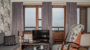 A living room with a sofa, a chair, a TV, and a table with candles. - Ylläs chalets 2301 by Interhome (Ylläsjärvi)