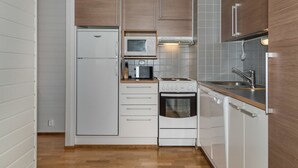 A compact kitchen with a refrigerator, microwave, stove, and sink. - Ylläs chalets 2301 by Interhome (Ylläsjärvi)