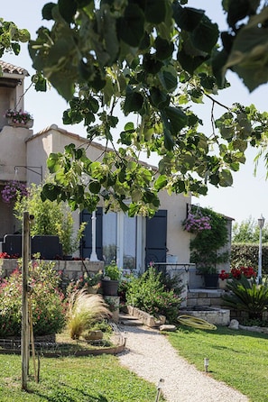 A garden pathway leading to a building with a stone wall and potted plants. - Chambre d'hôtes Les Cigales (Comps)