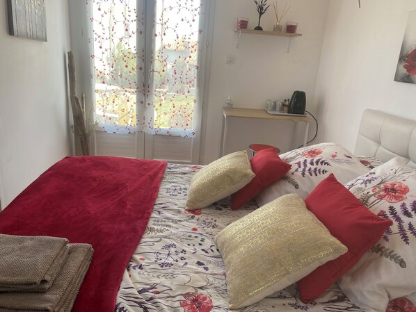 Un dormitorio con una cama, una manta roja y una colcha estampada.