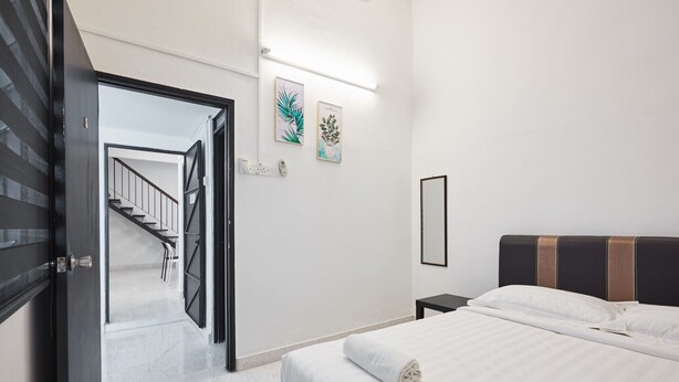 A hotel room with a bed, a nightstand, a mirror, and a door leading to a staircase.