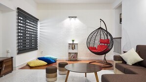 A modern living room with a hanging chair, a sofa, a coffee table, and a bookshelf.