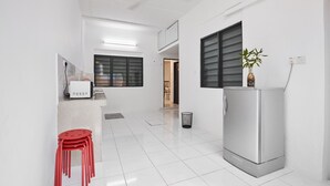 A modern kitchen with white cabinets, a refrigerator, and a dining area with red chairs.
