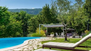 Ein Poolbereich mit Liegestühlen, einer Pergola und einem Steinweg, der zum Pool führt.