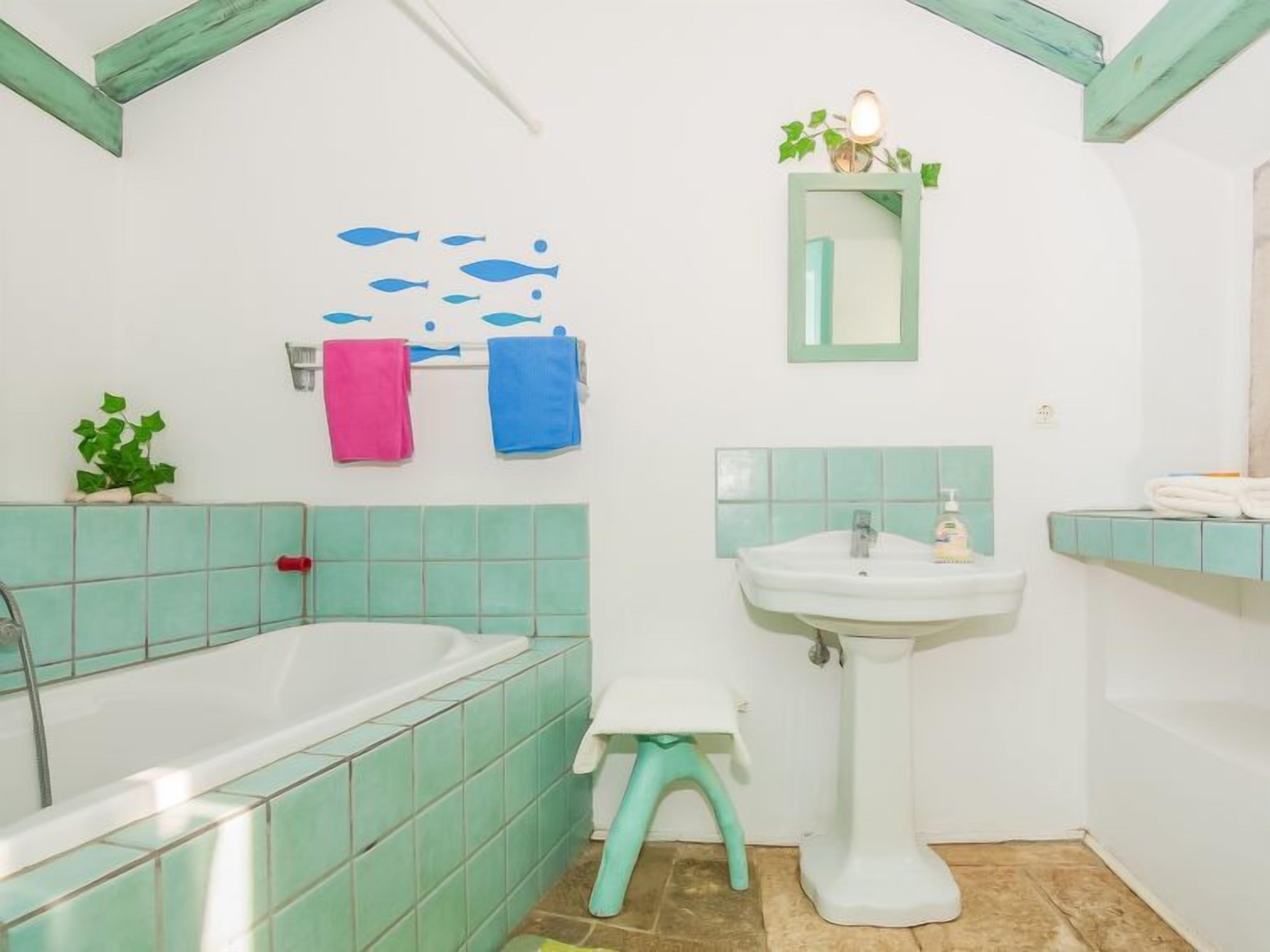 Een badkamer met een bad, wastafel en een klein krukje.