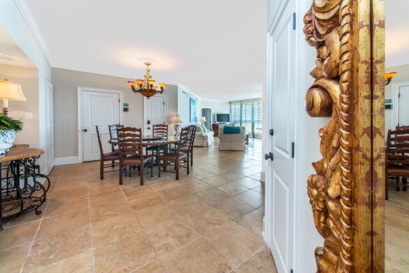 A spacious dining area with a chandelier, wooden chairs, and a table.