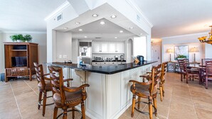 A spacious kitchen with a central island, white cabinetry, and a dining area with wooden chairs. - 🌊Beach Front Pool~Walk2Beach and Jetties~Gulf & Harbor Views~3BR East Pass 605 (Destin)