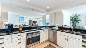 A modern kitchen with white cabinets, stainless steel appliances, and a black countertop. - 🌊Beach Front Pool~Walk2Beach and Jetties~Gulf & Harbor Views~3BR East Pass 605 (Destin)