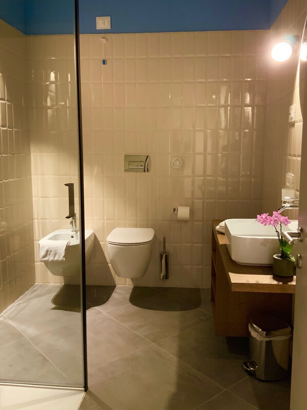 Un baño con cabina de ducha de vidrio, lavabo, inodoro y tocador con espejo.