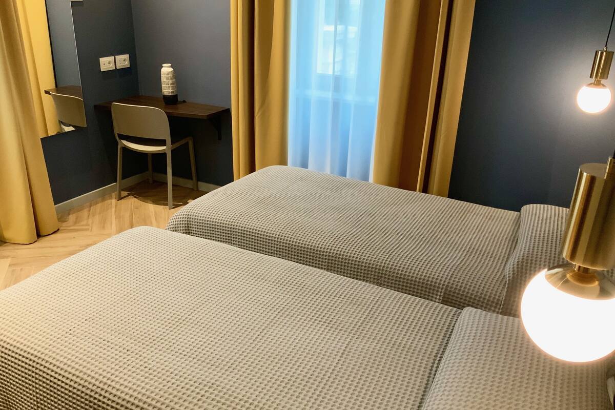 Een hotelkamer met twee bedden, een bureau, een stoel en een lamp.