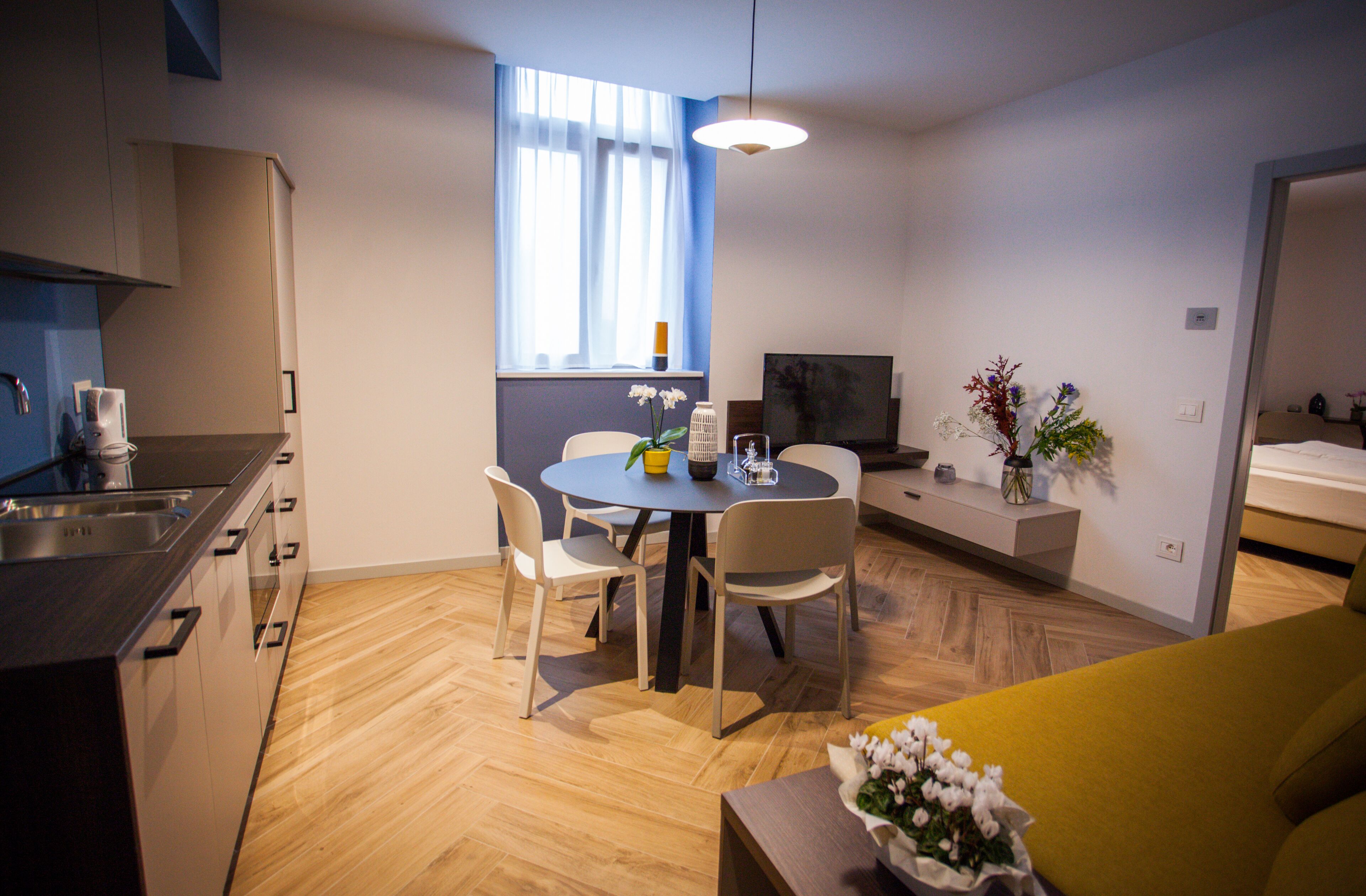 Eine moderne Küche mit Essbereich, Fernseher und Sofa.