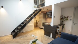 A modern interior with a staircase, a dining area, and a living space with a sofa and a small table with a plant. - Residenza Alto Garda (Riva del Garda)