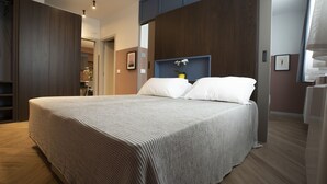 A modern bedroom with a large bed, wooden wardrobe, and a small desk area. - Residenza Alto Garda (Riva del Garda)