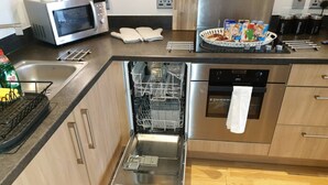 A modern kitchen with stainless steel appliances, a dishwasher, and a microwave. - Birmingham Garnet, 3 Bedroom Apartment (Birmingham)