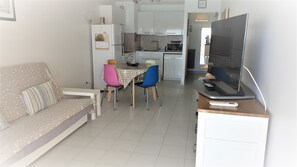 A compact living space with a sofa, a dining table with chairs, a kitchen area, and a television on a stand. - T3 in the heart of the city, on the waterfront, QUIET, Owners nearby (Le Lavandou)