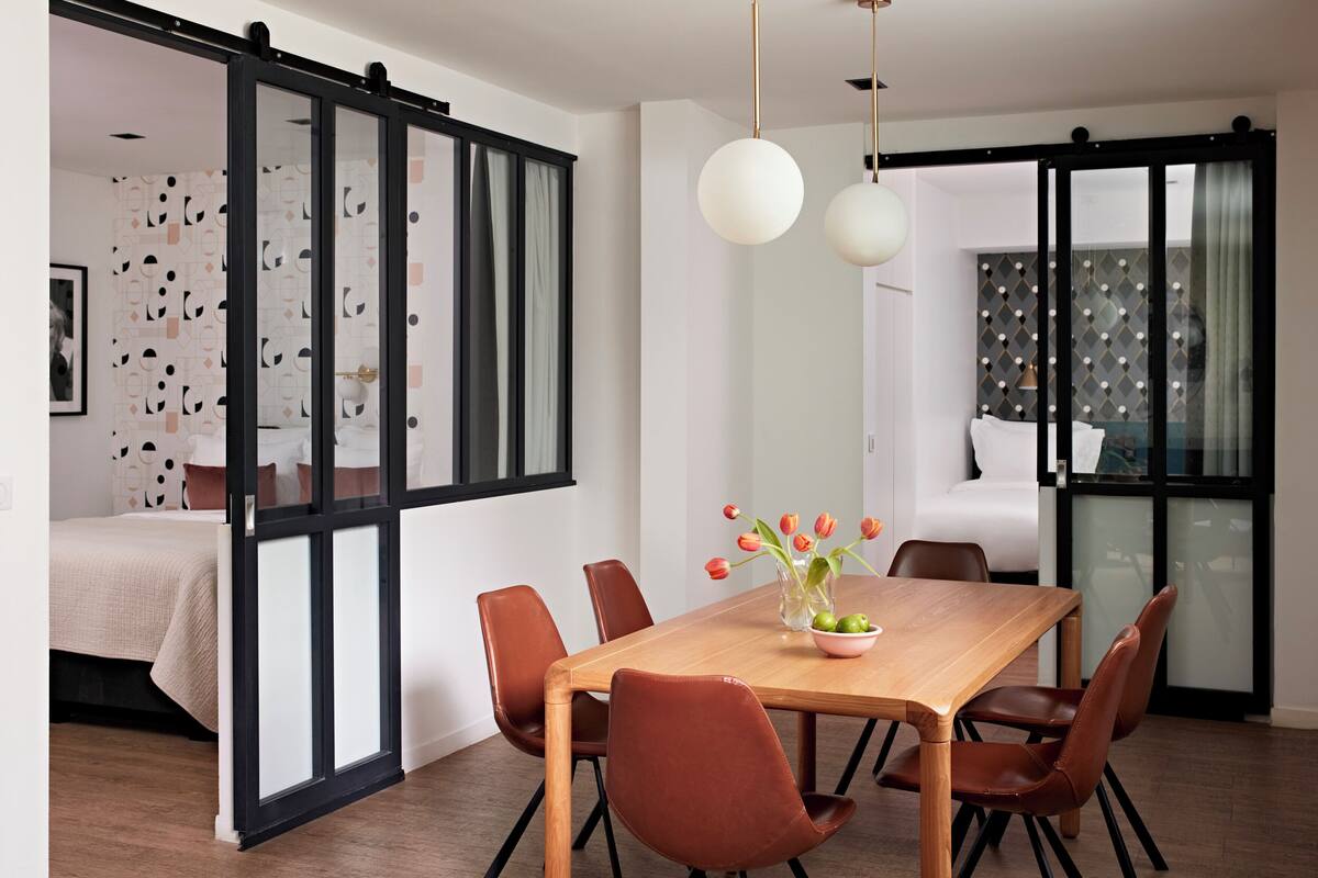 Un coin repas moderne avec une table en bois, des chaises marron et un vase de tulipes.