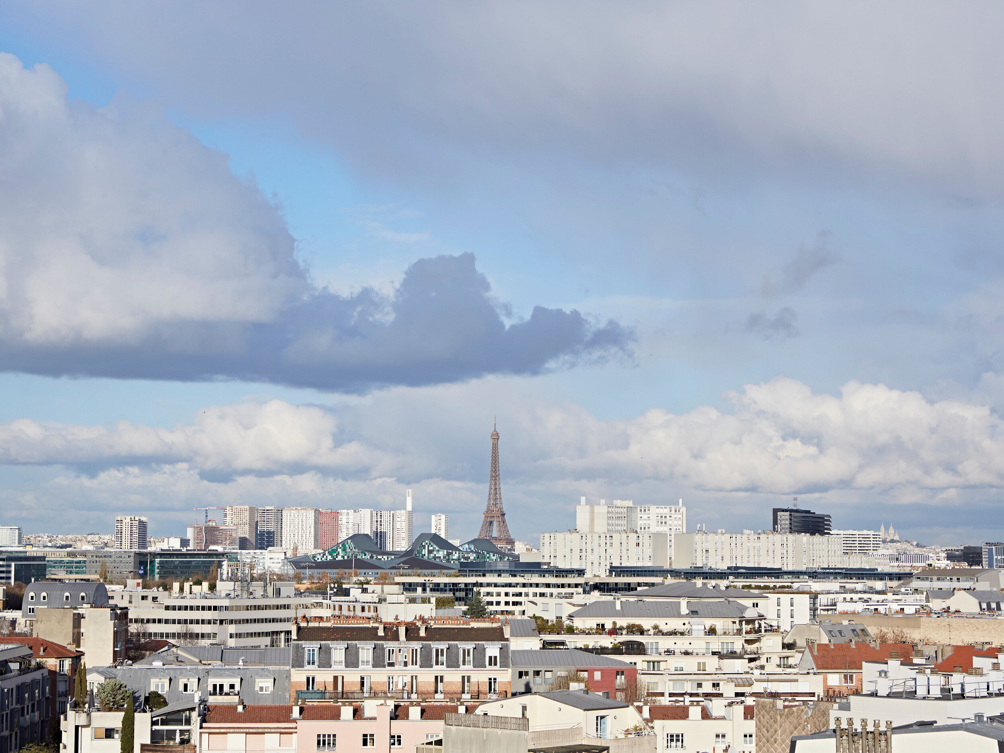 Une vue urbaine avec la Tour Eiffel en arrière-plan, entourée d’immeubles modernes et de quartiers résidentiels.