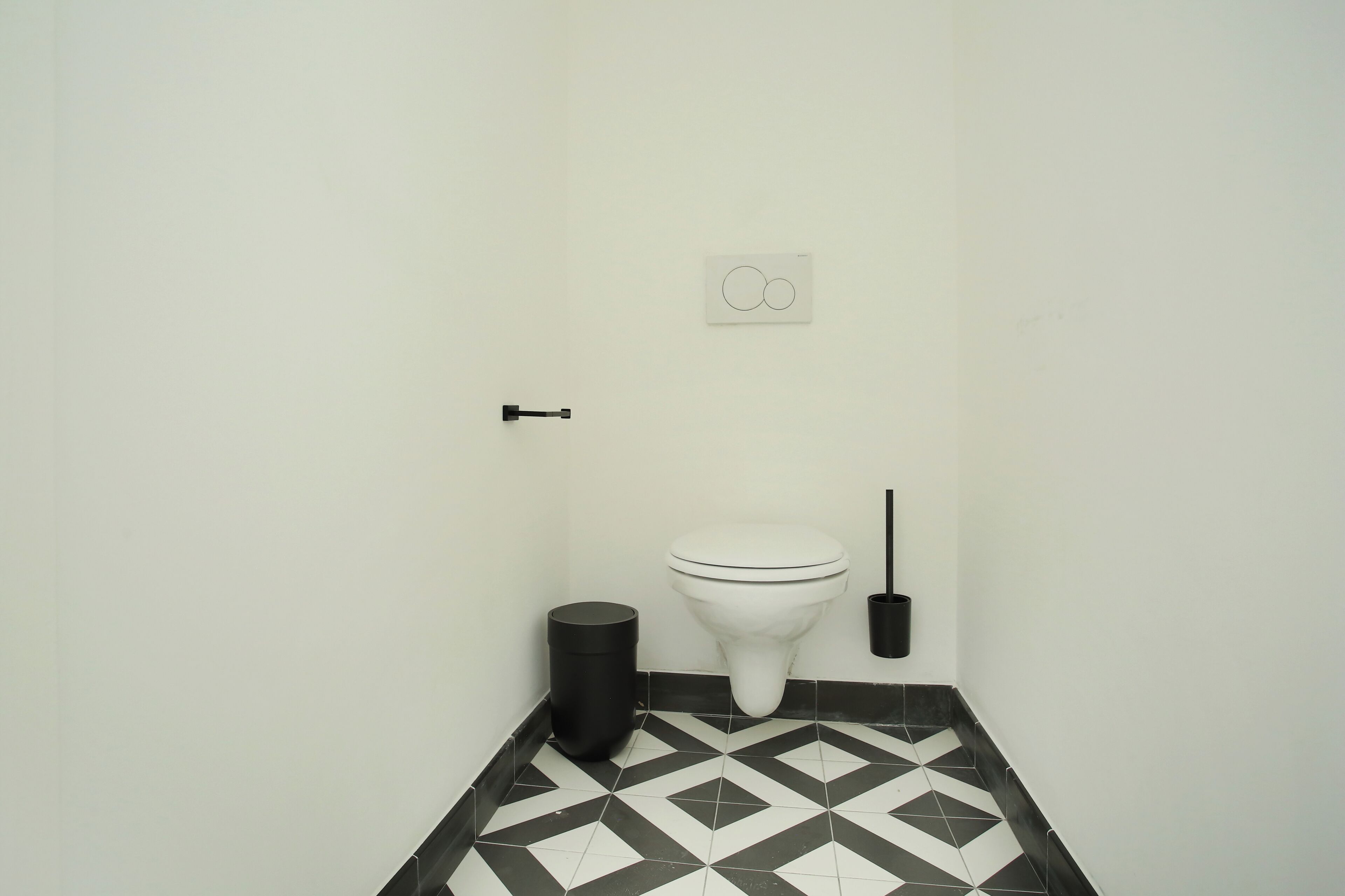Un bagno piccolo e pulito con il water, un cestino e uno scopino.
