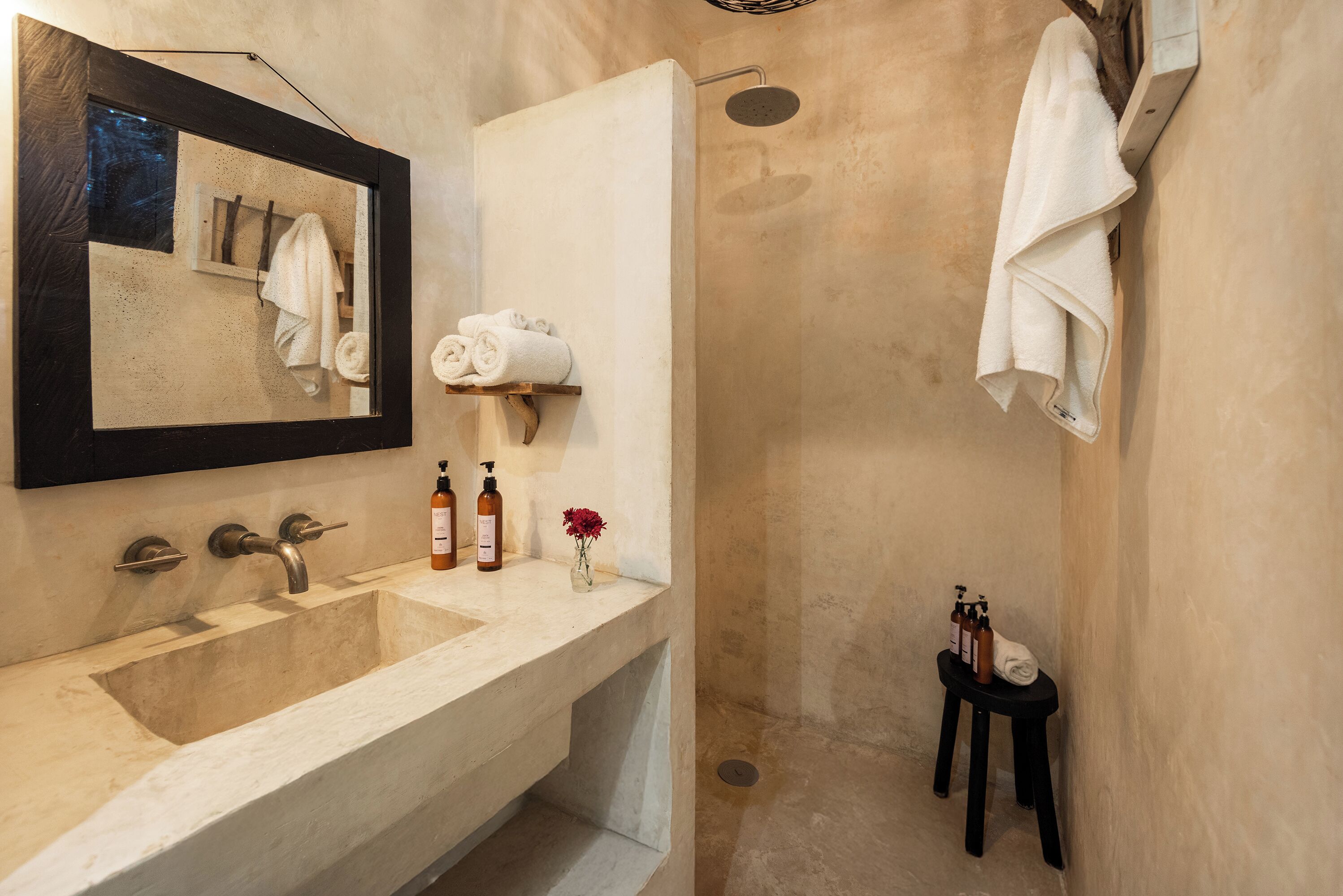 A bathroom with a large sink, a mirror, a shower, and towels on a rack.