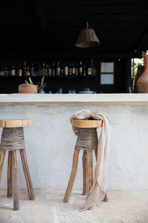 A bar area with two wooden stools, a white counter, and a hanging light fixture.