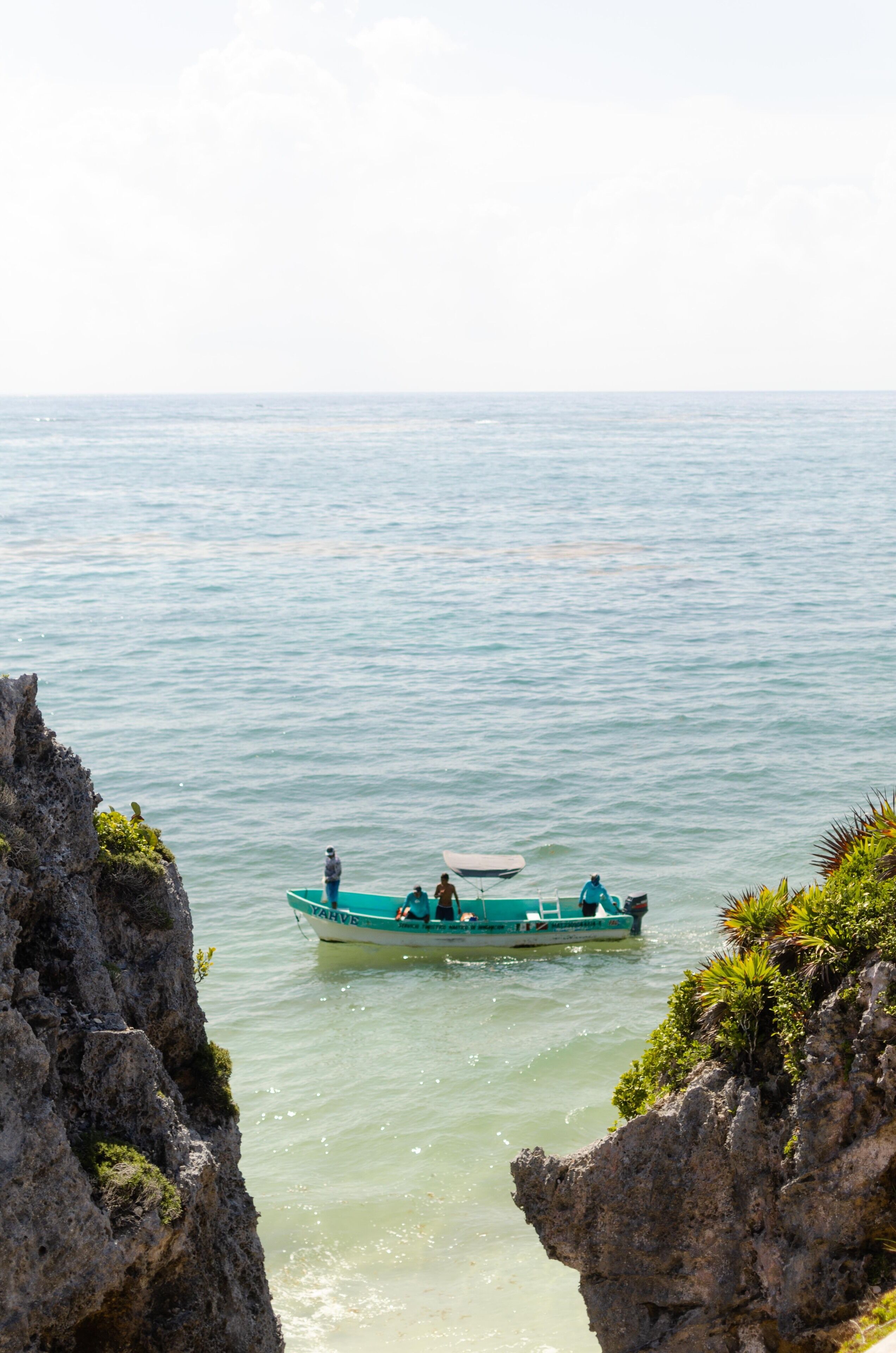 A boat on calm water with rocky cliffs on either side.