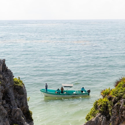 A boat on calm water with rocky cliffs on either side.