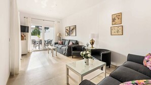 A spacious living room with a glass coffee table, a sofa, and a dining area with chairs. - Villa Catalina (Nerja)