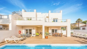 A modern two-story building with a rooftop pool, outdoor seating, and a clear blue sky. - Villa Catalina (Nerja)