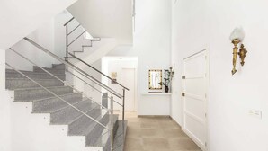 A modern interior with a staircase, a door, and a wall-mounted light fixture. - Villa Catalina (Nerja)