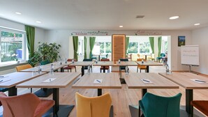 A conference room with multiple tables and chairs, a whiteboard, and a view of greenery outside. - Pension Freiheit (Pfronten)