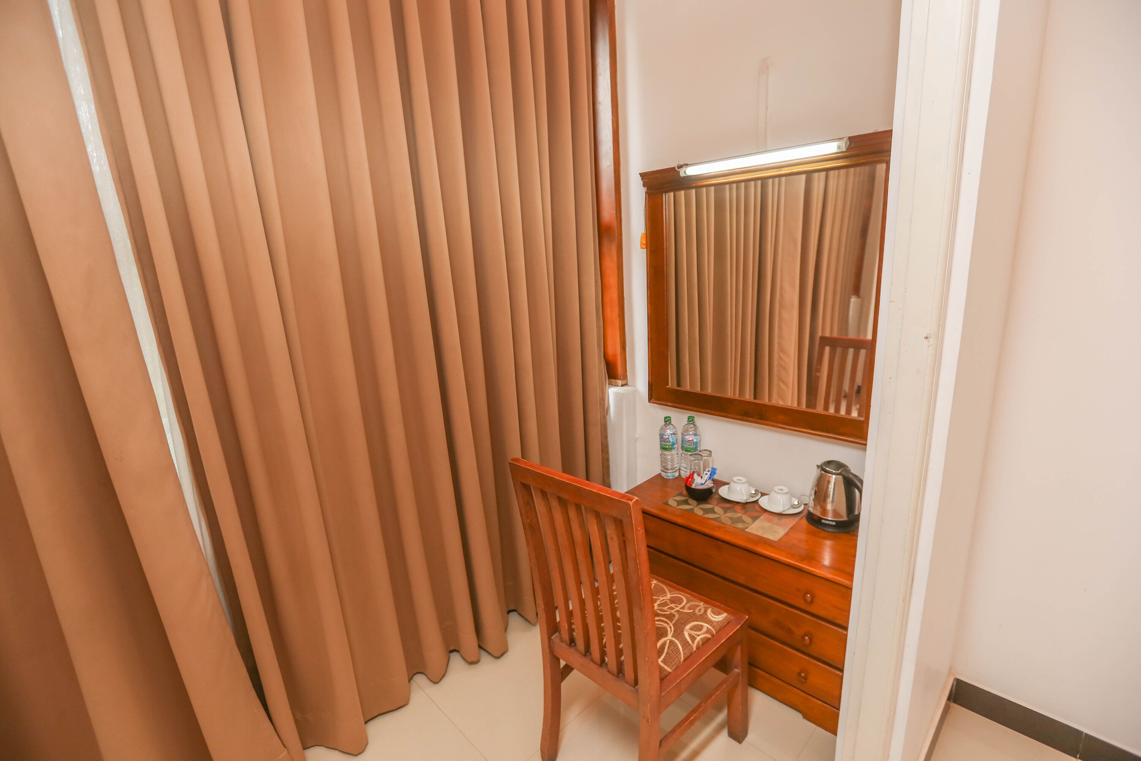 A room with a wooden desk, a mirror, and a set of drawers.