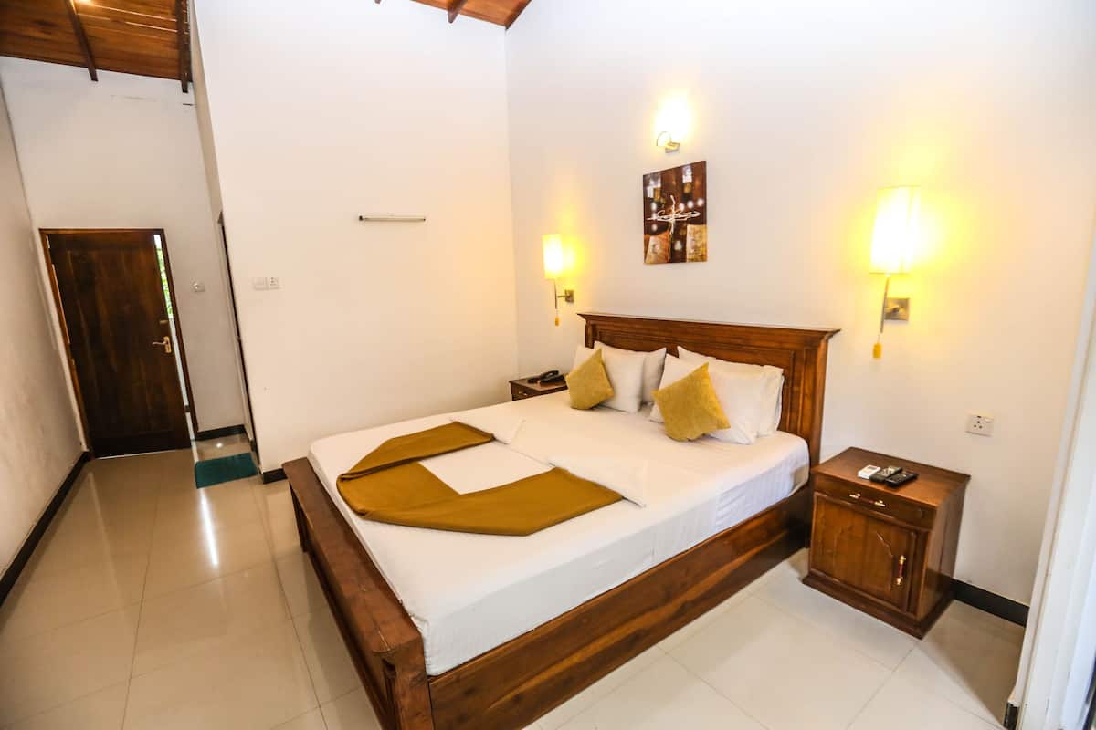 A neatly made bed with a wooden headboard, two bedside tables with lamps, and a small cabinet.