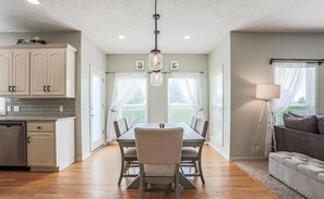 Enjoy meals in this dining area with a central table and comfortable seating, surrounded by a modern kitchen and a cozy sofa.