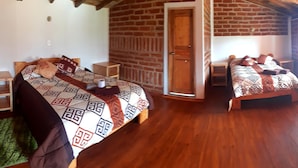 Une pièce chaleureuse avec deux lits en bois, un mur en briques et un plancher en bois.