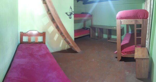 A small, narrow room with a bunk bed, a single bed, and a wooden chair. - Hostal Cloud Forest (Chugchilan)