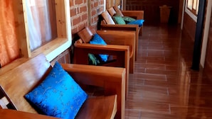 Une rangée de bancs en bois avec des coussins bleus, un mur de briques et un plancher en bois.