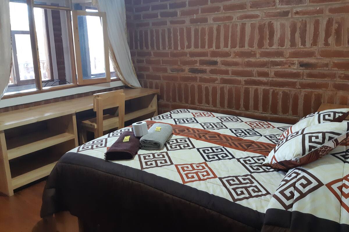 A room with a bed, a desk, and a window.