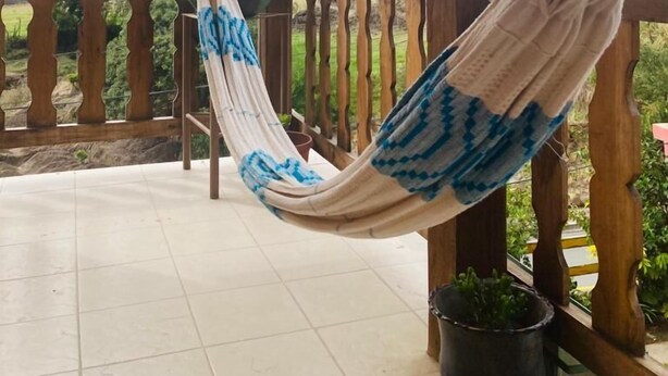 Un hamac sur un balcon avec vue sur les arbres et les montagnes.