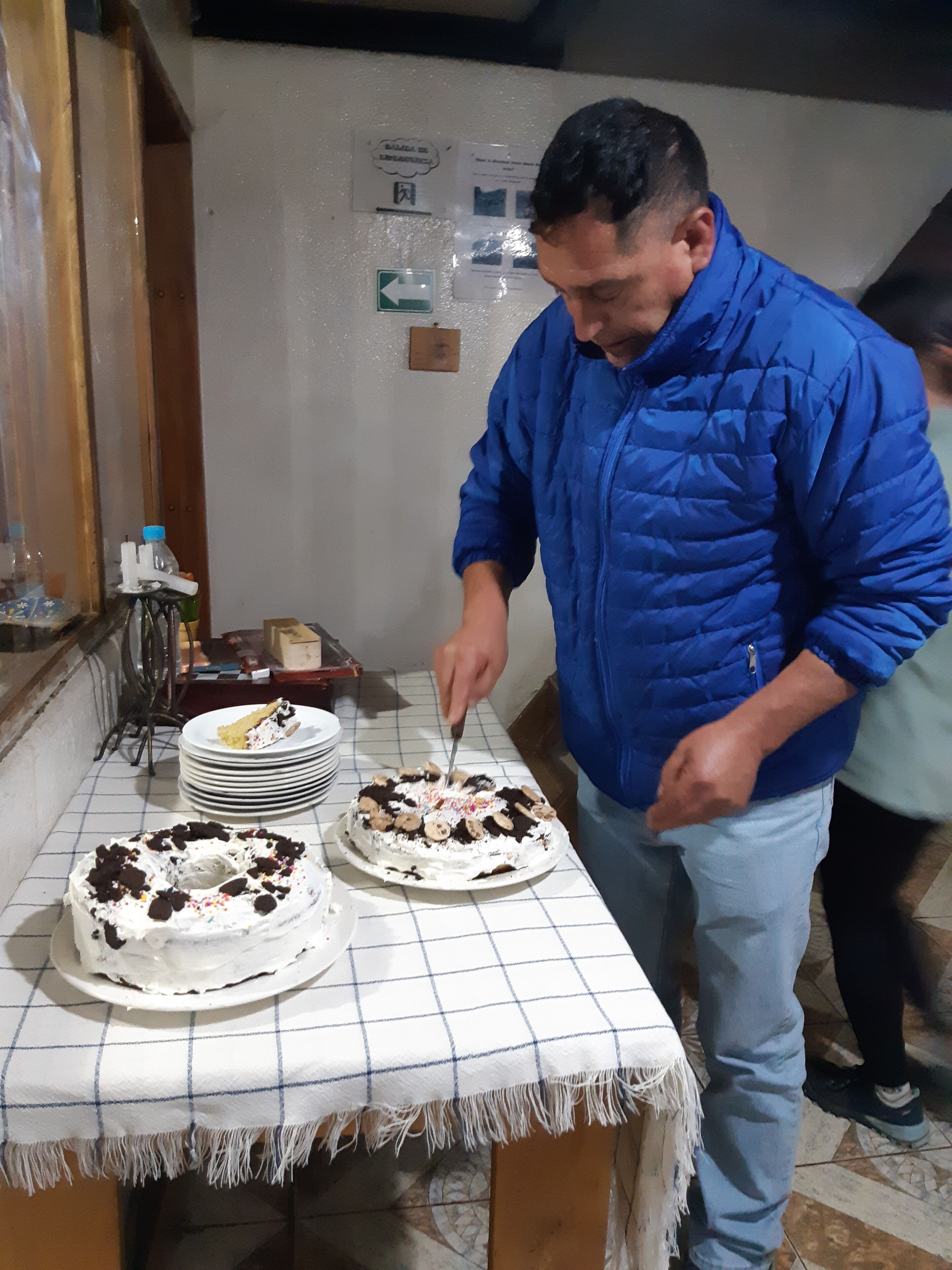 Un uomo che taglia una torta su un tavolo con tovaglia a quadri.