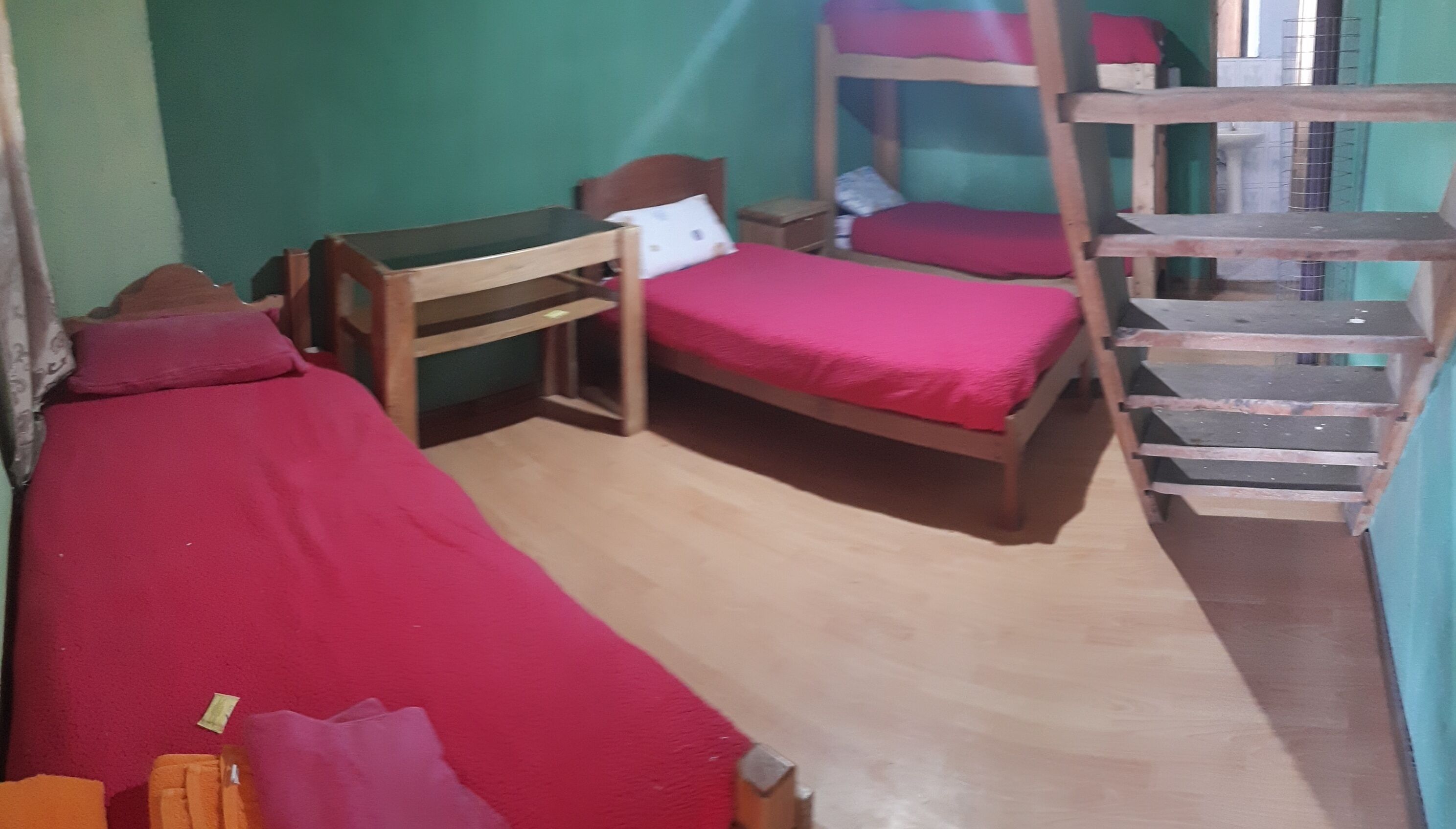 Ein Zimmer mit Etagenbetten, einem Einzelbett und einem kleinen Tisch.