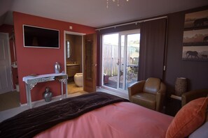 A bedroom with a bed, a desk, a chair, and a sliding glass door leading to an outdoor area.
