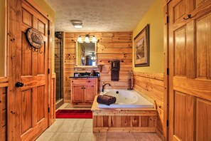 Une salle de bain rustique, avec une cabine en bois, une baignoire en bois, un lavabo et un miroir.